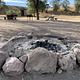 A stone-ringed fire pit on the ground with dark ashes in the center.