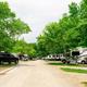 Wide view down an RV campground road showing multiple RV sites, trees and gravel roadway — a clear depiction of the park's RV pitching area. Image is from the property's 'ways to stay' section on the KOA Brown County page.