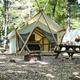 Glamping safari-style tent with picnic table and fire pit in a wooded setting — aligns with the property’s ‘Glamping’ promotional image and shows on-site glamping accommodations.
