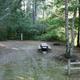Individual tent/campsite area with picnic table, fire ring and tree buffer adjacent to water — useful detail photo showing a typical tent/campsite setup on the grounds.