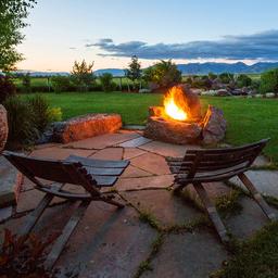 Outdoor firepit seating with landscaped grounds and distant mountain views — depicts guest amenity and scenic setting (gallery image).