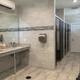 Restroom with two sinks, soap dispensers, hand dryer, lockers, and a closed door.