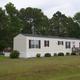 Large, well-framed photo of a rental/mobile home on grassy lot with trees and lake visible behind — useful to illustrate on-site rental housing (source: Rentals page, rentimages/3.jpg).