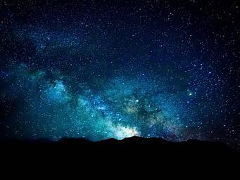 Night sky with the Milky Way over dark sand dunes.