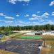Wide scene showing recreational facilities including pool area, fenced courts and surrounding grounds — useful for guests evaluating on-site amenities (Gallery page).