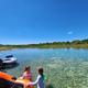 Clear daytime riverside scene with inflatable tubes and people at the water’s edge — shows the campground’s river access and recreational use referenced throughout the site.