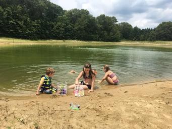 Pond/beach area with children at the shoreline — depicts on‑site water feature and sandy shore used by guests (page caption references the pond).