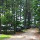 Pathway view into the campground showing campsites and surrounding trees — good for illustrating overall circulation and wooded setting.