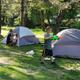 Daytime photo of tent camping area with multiple tents and a child playing — good representation of tent sites and family activity on the grounds (homepage).