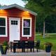 Clear photo of a red cabin with patio furniture and landscaping — matches the site's Cabin Amenities image and shows an on‑site lodging unit and grounds.