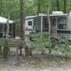 Campsite/RV pitch among woods with landscaping and seating visible — represents typical tent/RV site on the property (from site slider/gallery). 