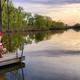 Shows a fisherman and child on a dock at one of the campground lakes at sunset — clear scene of on-site waterfront and fishing amenity (used as hero image on the site).