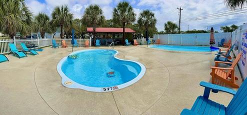 Panoramic/ground-level photo of the two pools and pool deck with chairs — good close-up of primary guest amenity and seating areas (matches site pool images).