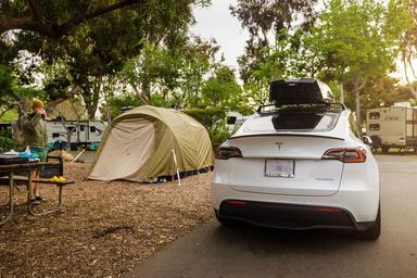 Shows a tent campsite next to a vehicle in a treed campsite loop, with picnic table and RVs in the background — a typical on-site tent/RV pod photo from the campground's 'waystostayphotos' collection.