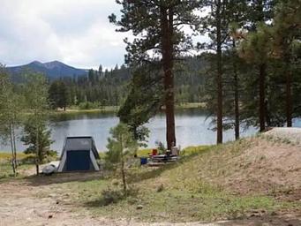 Tent, picnic table with mountains and lake in backgorund