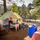 Tent campsite photo with camp chairs, tent, picnic table and nearby campground features — good representation of tent camping options and on-site atmosphere.