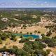 Aerial view of oak-dotted Hill Country land stretching to the horizon, with a small pond