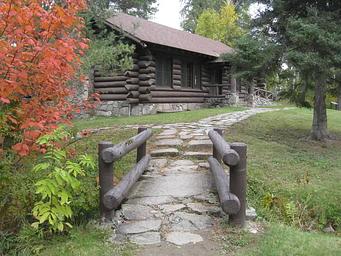 Picture of rock-lined path and log building.