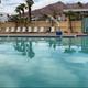 Aerial/drone view showing the main pool area, pool deck, lounge chairs and surrounding RV sites with palm trees and mountains in the background — good overall overview of the resort layout (image hosted on the property's About page).