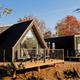 Close exterior photograph of a modern A-frame style cabin with deck and landscaping — corresponds to the cabins described on the main site and ‘Ways To Stay’ content.