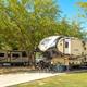 RV site with large fifth-wheel trailers, paved pad and shade trees — clearly shows RV accommodations and site layout on the property (from the resort’s website).
