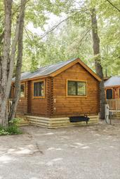 Wood cabin exterior among trees — clear photo of one of the campground’s rental cabins shown on the property pages.