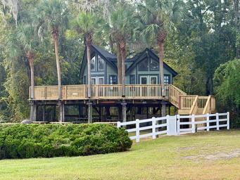 Distinct elevated cabin/house on stilts with surrounding grounds and palms — useful scenic lodging shot. Source is the property's stay page, indicating it's on‑site accommodation.