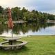 View of the campground’s lake/beach area with swim-line buoys, picnic table and shoreline — useful for showing waterfront recreation on the property. Shown on the site’s homepage context.