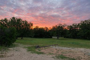 Scenic sunset view over grassy area and trees on the property — useful for conveying the park’s landscape and ambiance (featured as homepage/social image).