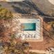Aerial view of the resort pool and surrounding deck and lounge chairs — clear overview of an on-site amenity and its relationship to paved roads and landscaping (supports property facilities).