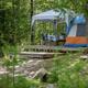 Forest campsite with raised wooden platform, tent and picnic setup — clearly shows a tent site and typical campground infrastructure (from the property’s gallery page).