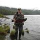 Fisherman holding coho salmon in front of Anan Lake