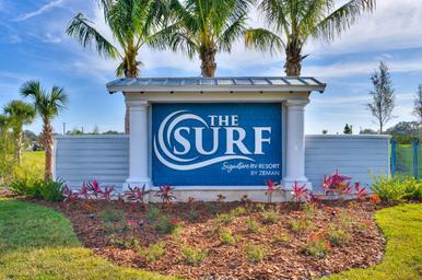 Entrance sign photo with 'The Surf' branding, landscaping and palms — establishes property identity and arrival experience (gallery / site signage image).