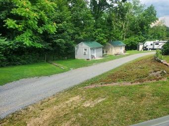 Exterior view of two small cabins along a gravel road with RV visible in background — useful to show cabin accommodation options and campground layout (from the property’s cabins/gallery section).