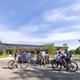 Photo showing the main facility/building with people and bikes in the foreground (parking/entry area). Appears on the home page and represents guest facilities, parking and trail access at the property.