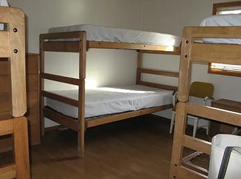 Three sets of twin wooden bunk beds with mattresses in a bedroom