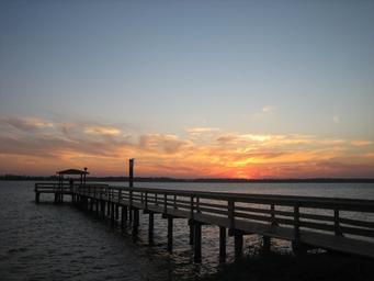 Long wooden pier extending into the river at sunset — strong scenic shot demonstrating the resort’s river access and waterfront atmosphere (from the property homepage/amenities).