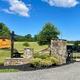 Entrance/gate photo with the Greystone sign, landscaping and park buildings visible — good for identifying property access and curb appeal (Amenities page).