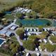 Aerial drone/photo overview showing the campground layout: central stocked pond, surrounding RV loops, pool and buildings — clearly the property from the site’s social/video hero and ideal as an overview image (page social image/video).