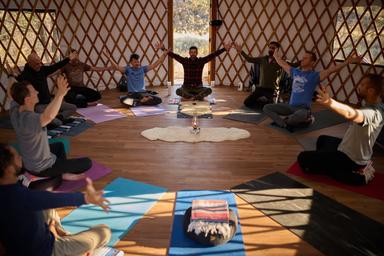 Interior of a yurt or group space with people doing yoga/meditation — demonstrates on-site program space and activities available to guests (from the property's gallery).
