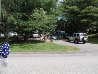 Clear photograph of RV sites and roadways with shaded trees and vehicles — depicts typical RV pitch layout on the property (from the site’s gallery).