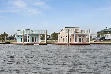 Two waterfront houseboats/floating homes viewed from the water — good overview of the marina-facing rental units and shoreline context; appears in the site photo gallery (image-2-new-1.jpg).