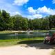 Wide view of the pond/lake with a golf cart in foreground and activity on the water — good overall site view of the campground’s lake and access road. Sourced from the Weekend Camping page on the property site.