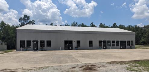 Exterior view of the clubhouse/amenity building (panoramic crop) with parking/picnic benches in front — useful building/facilities photo clearly on the property.