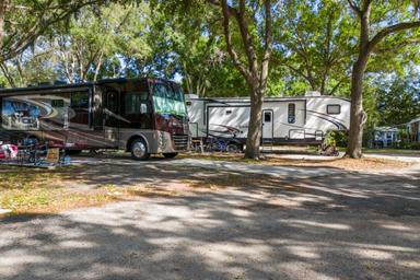 Shaded RV parking pads and large motorhomes on landscaped sites — clear photo of typical RV sites from the campground gallery.