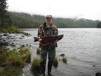 Fisherman holding coho salmon in front of Anan Lake