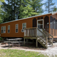 Clear exterior photo of a deluxe cabin on the property showing screened porch, picnic table and fire ring — matches the site’s cabin inventory pages and demonstrates accommodation type and setting.